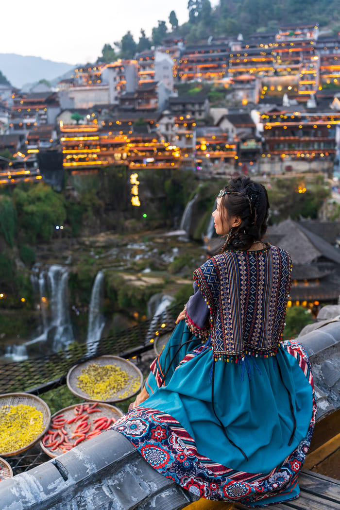 Mujer con traje tradicional viendo al horizonte en la ciudad Lijiang, China.