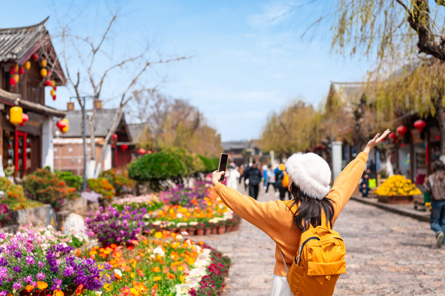 Turista de sueter amarillo disfrutando en Lijiang; china.