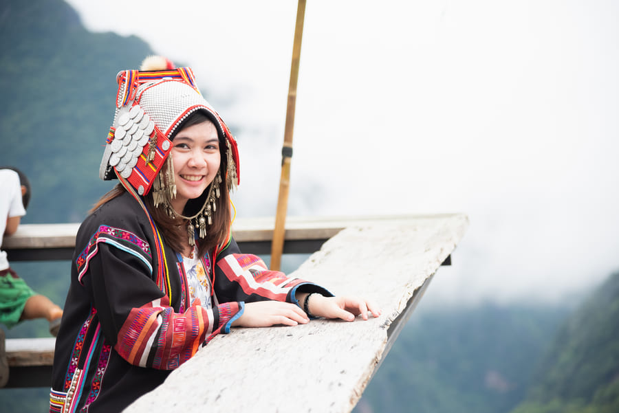 Mujer joven mhong con tocado en la cabeza, sonriendo en China.